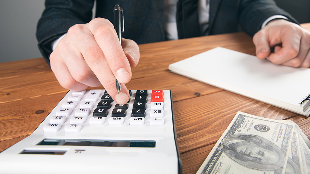 Understanding Closing Costs: A Breakdown for Buyers and Sellers Hand on calculator at closing on a home